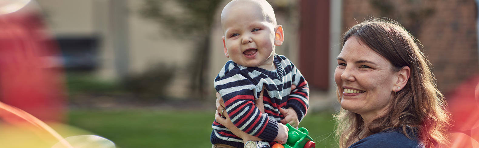 a smiling mother holds up a baby