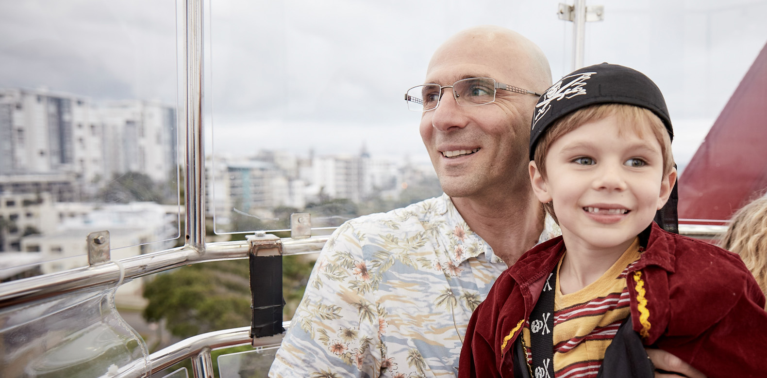a man and his son are smiling with a view of the city in the background