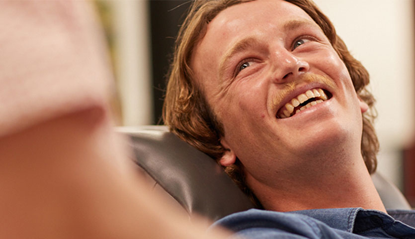 a donor is smiling sitting back in a seat looking up at a staff member