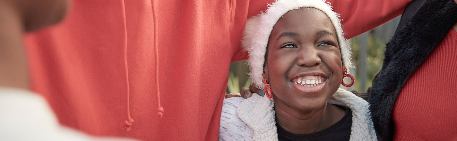 close up on a happy young girls face. She's being embraced by her family.