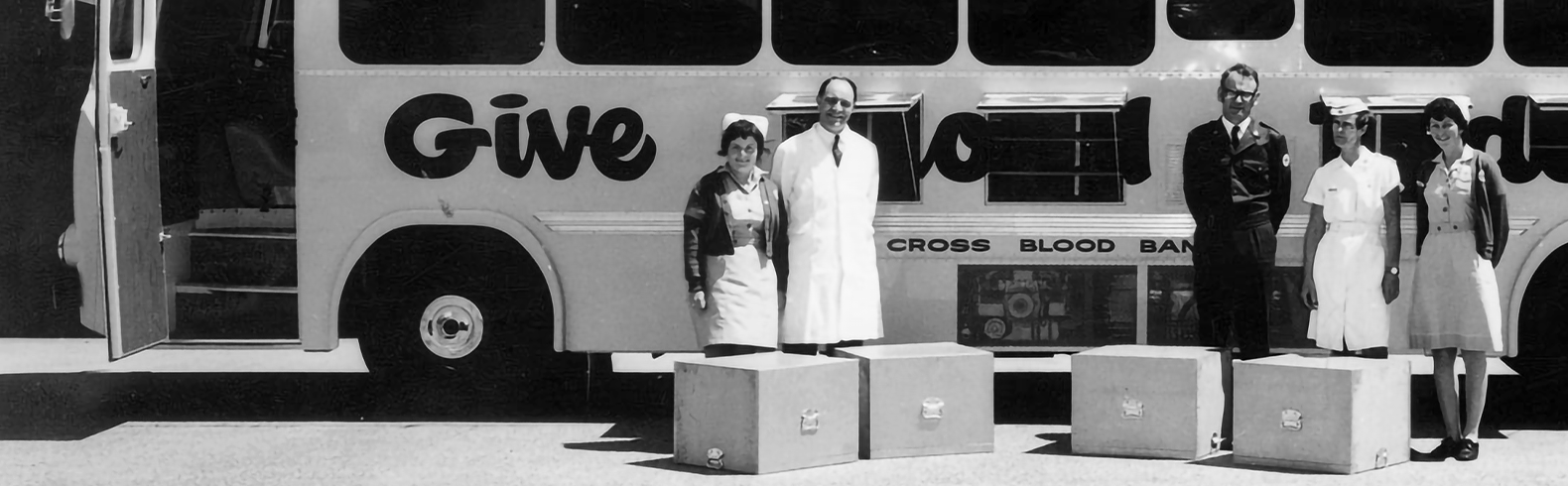 1940s photograph, black and white. 3 female nurses and 3 men standing in front of 'Donormobile' bus.