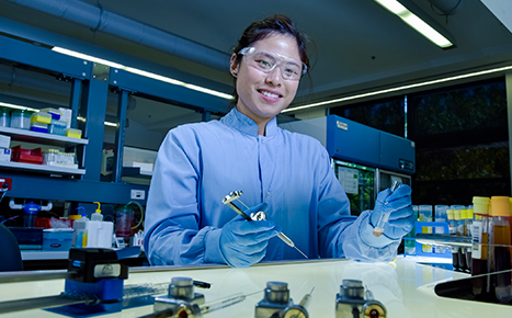 a scientist is in a laboratory wearing blue gloves and protective glasses while holding a test tube