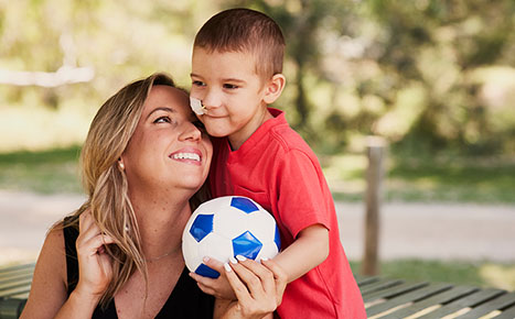 photo of Candice and River hugging, Candice is seated and smiling up to River who is holding a soccer ball