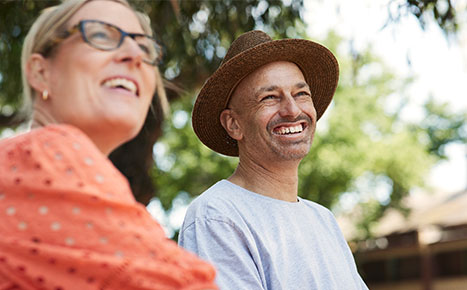 photo of Jase and Sarah outdoors on a sunny day, they're looking away and smiling