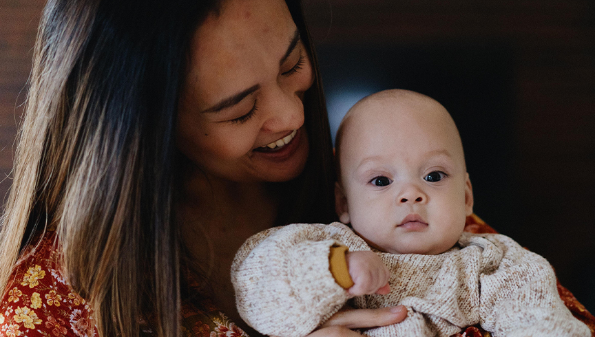 young woman smiling while holding her baby son