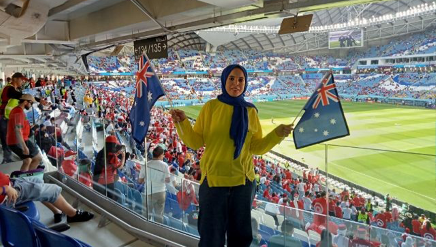 woman in a hijab holding up the australian flag at a sports stadium