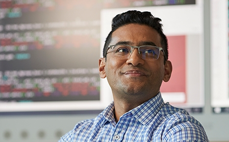 photo of doctor surendra karki, he is wearing a blue checked shirt and glasses and smiling off camera