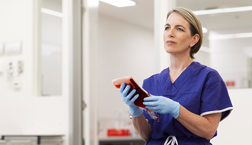 photo of nurse emma wearing a blue top and gloves holding a blood bag