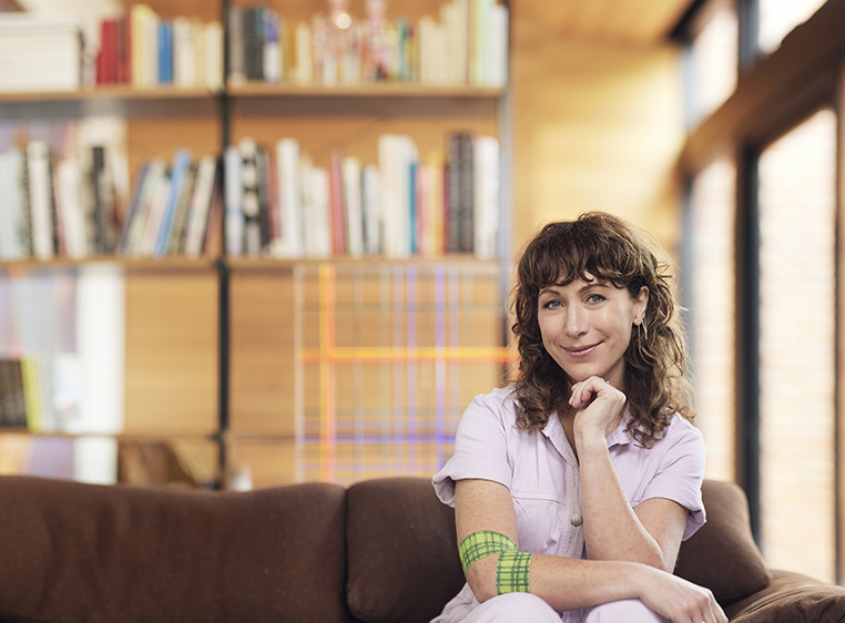 Lisa Gorman sitting down on couch in front of bookshelf