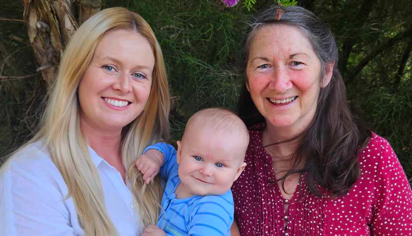 two women and a little baby boy smiling