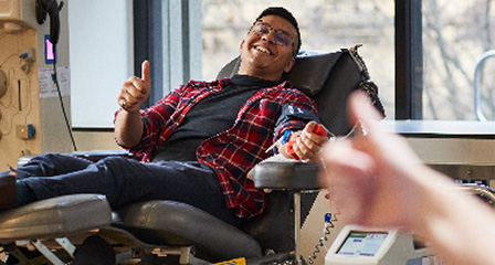 a donor in a chait giving a thumbs up and smiling