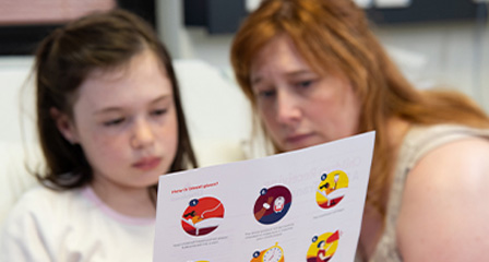a child and parent are reading an information sheet