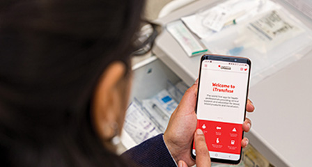 close up of a doctor using the itransfuse app on their smartphone