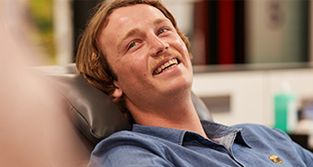 a male giving a donation in a chair smiling