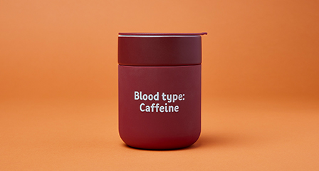 a reusable travel mug with blood type caffeine written on it