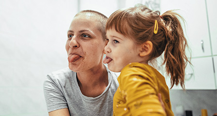 a mother and daughter laughing and poking their tongues out