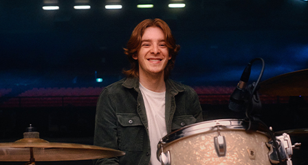 a man seated behind a drum kit on stage