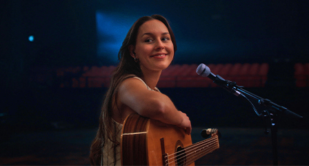 a woman playing guitar on stage