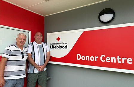 image of two middle-aged men in front of a Lifeblood donor centre sign