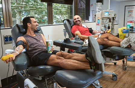Image of two young male donors donating plasma next to each other