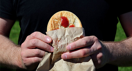 hands holding a pie with sauce