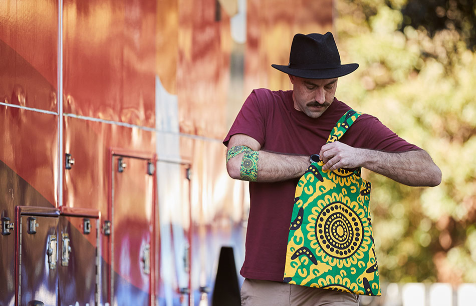 a man is wearing a tote bag around his shoulder, the tote bag is featuring the brad hore design