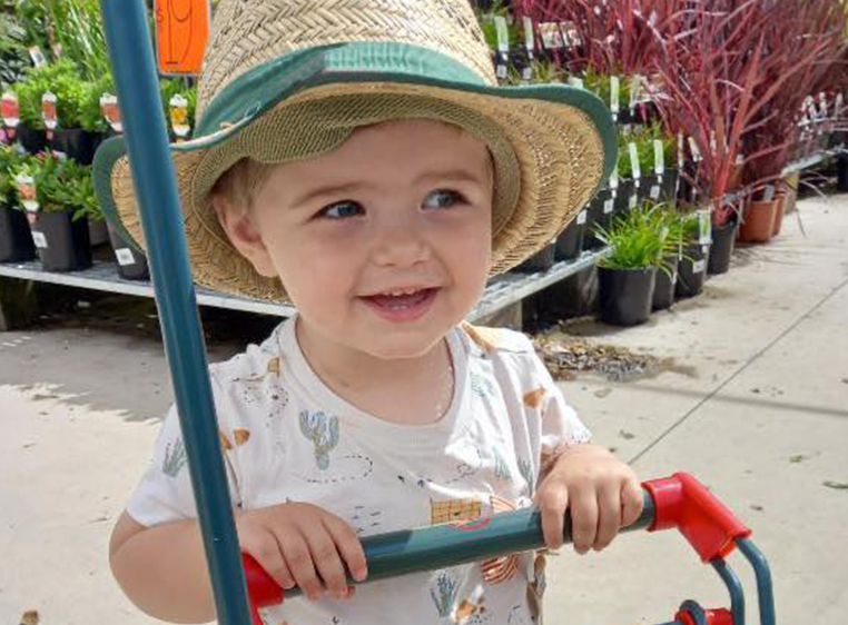 photo of recipient casey smiling and wearing a straw hat in front of some potplants