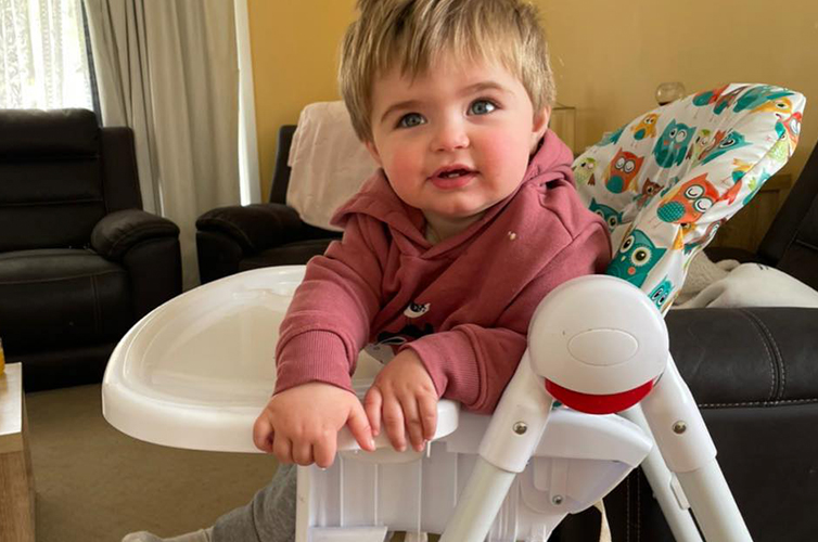 photo of recipient casey sitting on a high chair wearing a red hoodie