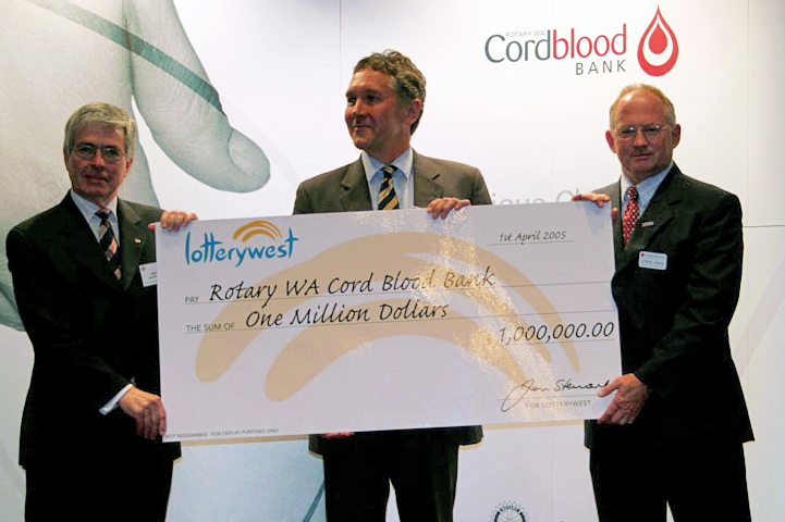 three men holding lotterywest cheque for $1 million dollars in front of Cordblood Bank sign
