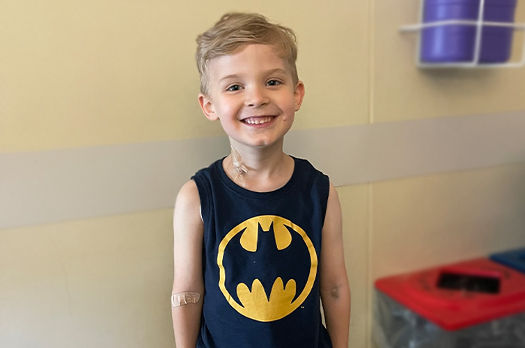 young boy with a batman tshirt smiling at the camera