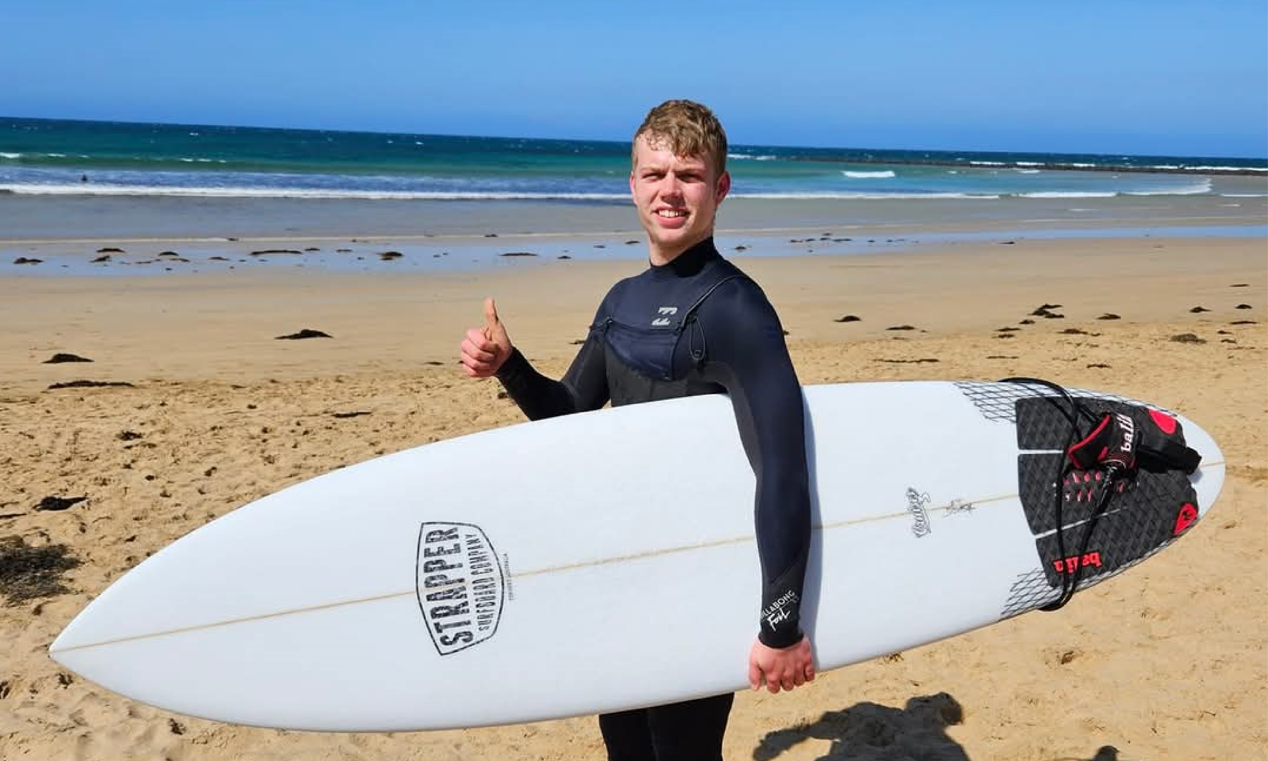 image of young male donor holding a surfboard on a beach'