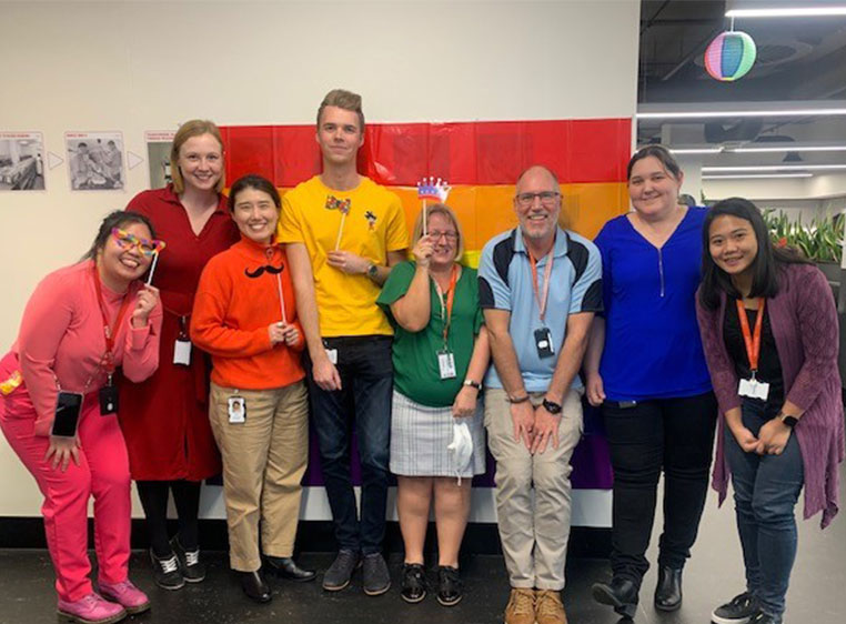 photograph of a group of lifeblood staff members wearing different coloured outfits and costume props and smiling at the camera