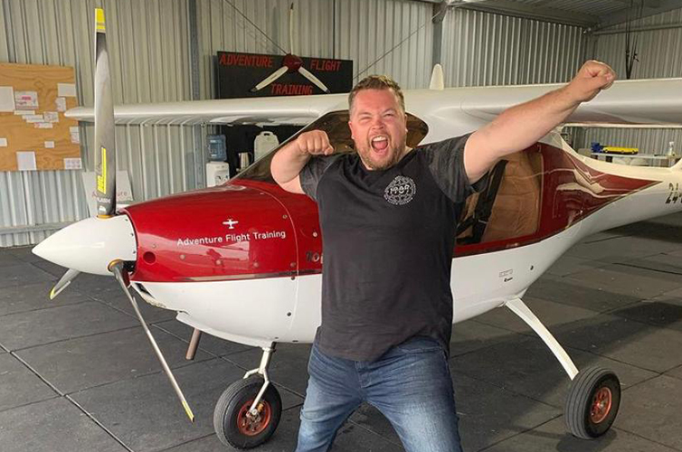 man with his hands in the air in front of an airplane