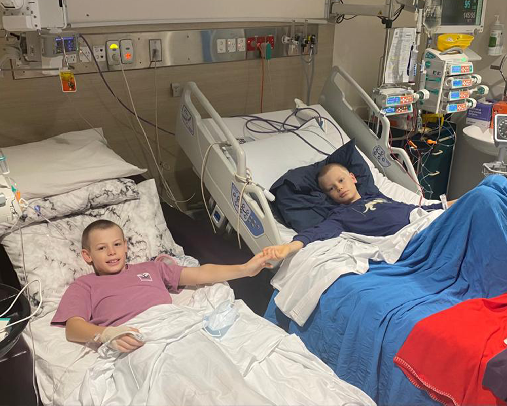 two young boys in hospital beds smiling at the camera