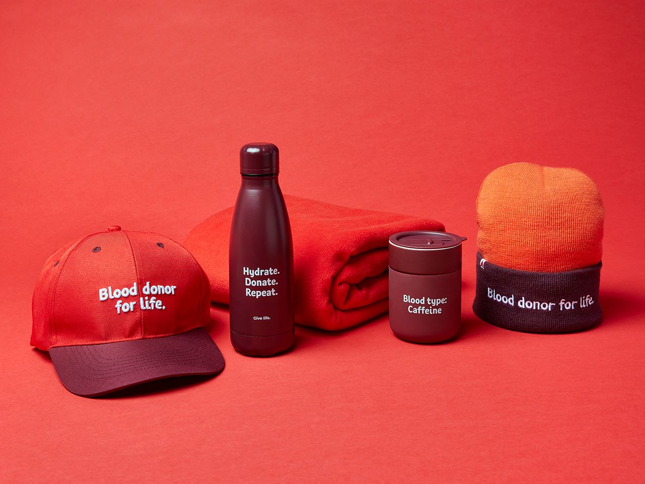a cap, stainless steel water bottle, blanket, travel mug and beanie
