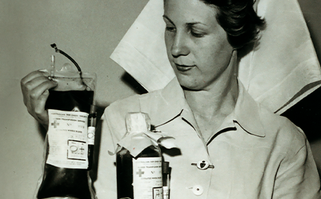 Black and white image of female nurse holding blood bag