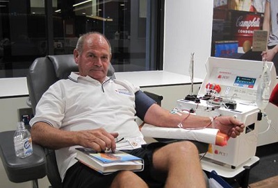 donor paul is sitting in a chair during a donation and reading a book