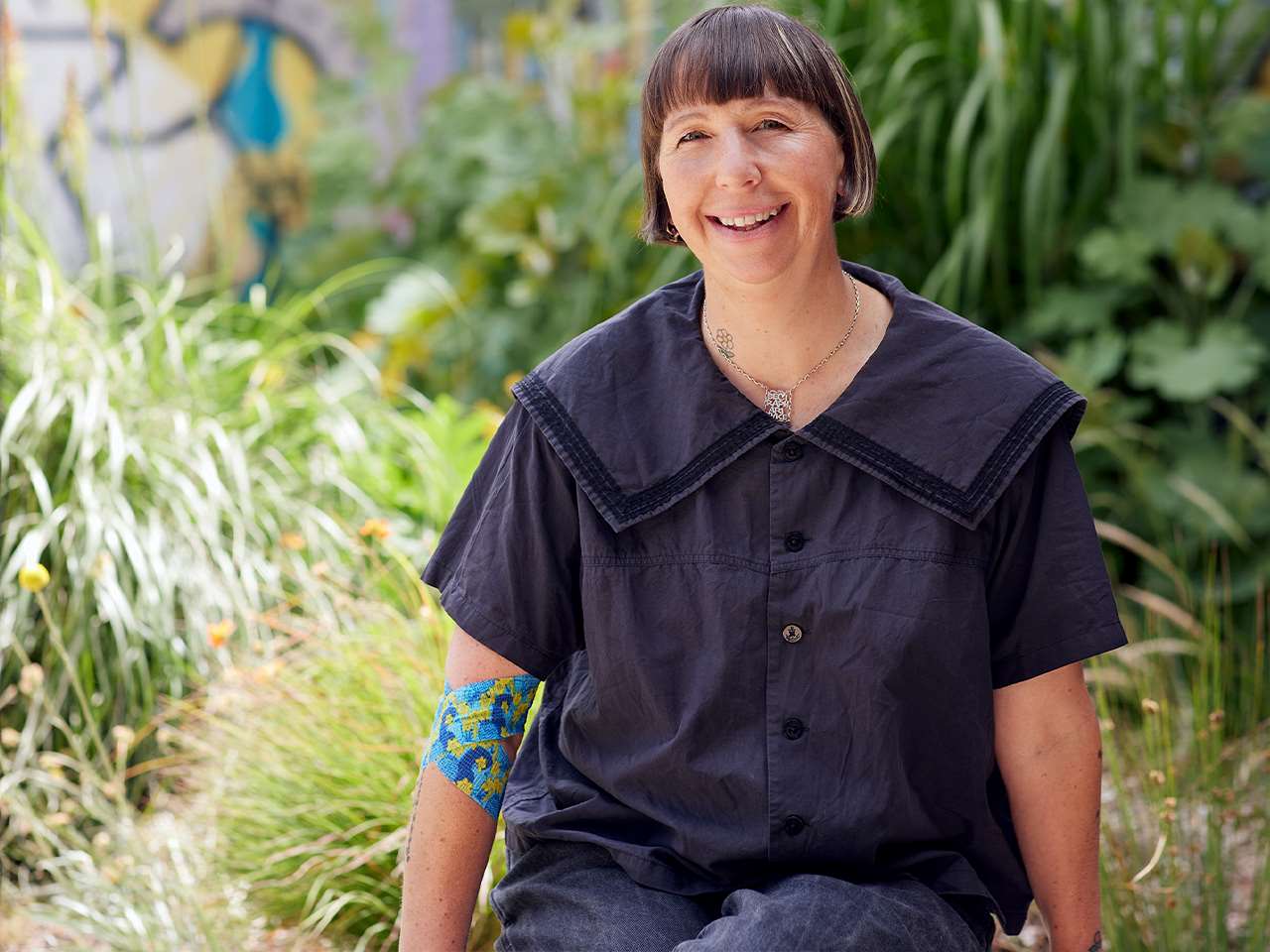 photo of artist Beci Orpin sitting in a green garden and smiling at the camera