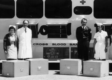 black and white historical photograph of donor staff standing in front of a bus