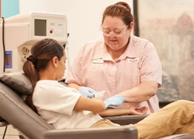 Nurse assisting a female donor as she donates blood