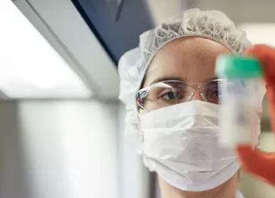 close up of a lab worker holding up a small container of milk