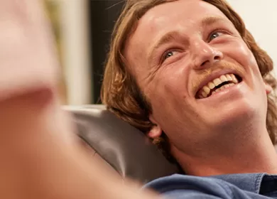 a donor is smiling sitting back in a seat looking up at a staff member