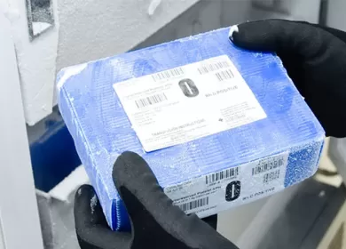 a blue frozen blood box is being taken out of a freezer by a scientist wearing gloves and a gown