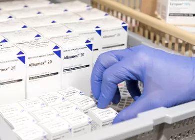 close up of a gloved hand picking up a small box from a basket