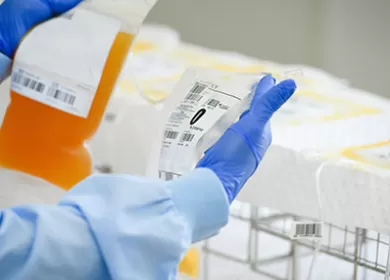 close up of a scientist examining donations, wearing a blue gown and gloves