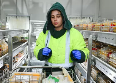 a scientist is wearing protective gear and pushing a trolley in a large freezer room