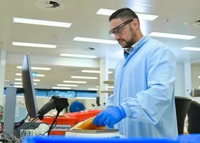 a scientist is wearing a blue gown and gloves and is scanning a donation
