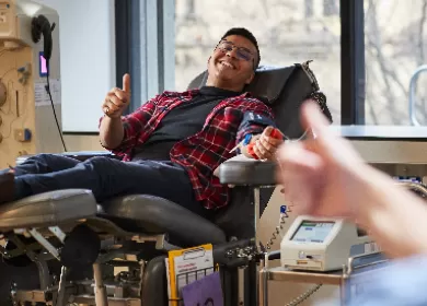 photo of a donor sitting back in a chair during a donation smiling and giving a thumbs up