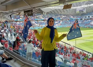 woman in a hijab holding up the australian flag at a sports stadium