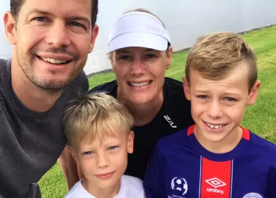 Man and woman with two young sons outdoor smiling at the camera